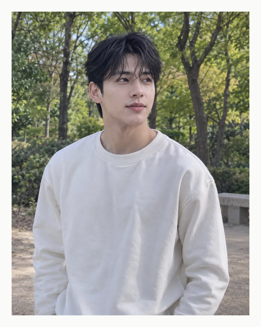 흰 테두리 안에 초록 숲을 배경으로 흰 맨투맨 차림으로 선 모습
