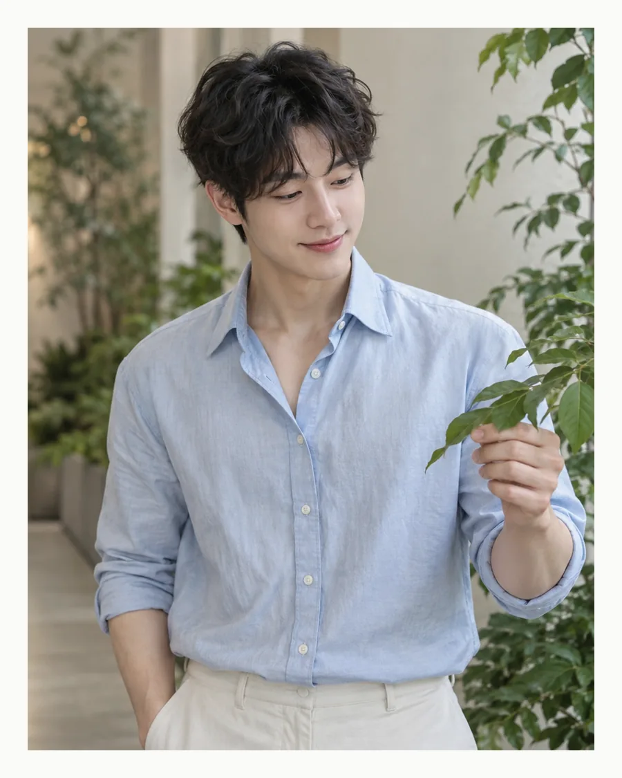흰 여백 안에서 연하늘색 셔츠 차림으로 초록 잎을 만지는 모습